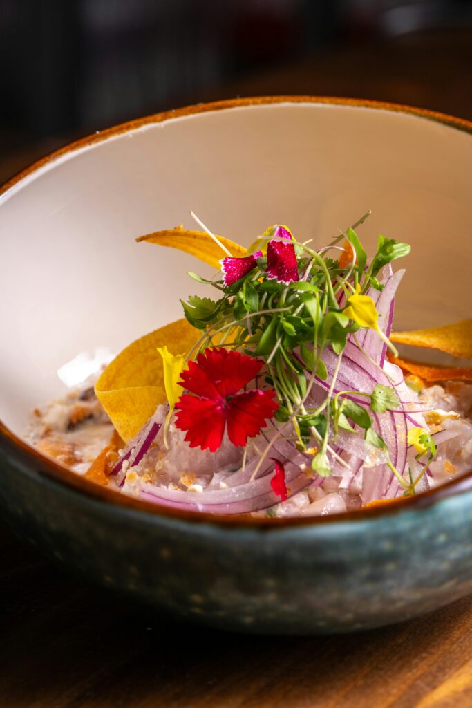 Artistic presentation of gourmet ceviche topped with microgreens and edible flowers.